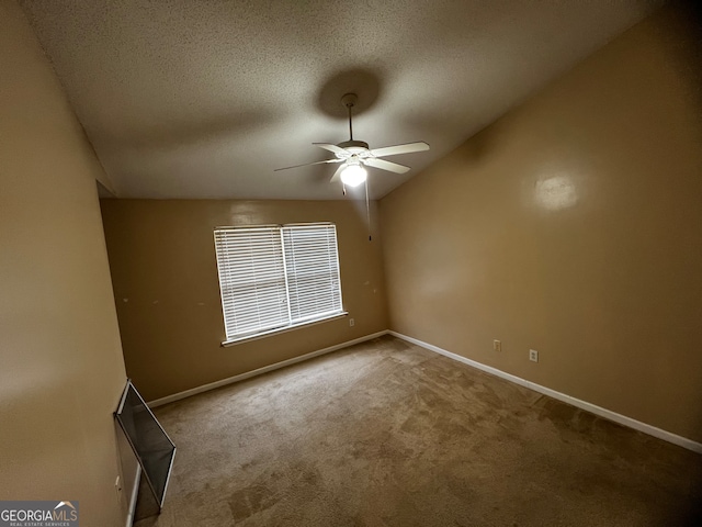 carpeted spare room with ceiling fan, a textured ceiling, and vaulted ceiling