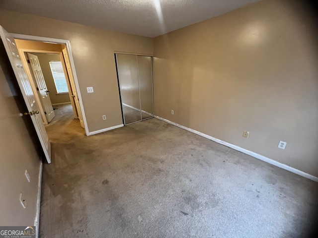 unfurnished bedroom featuring carpet flooring, a textured ceiling, and a closet