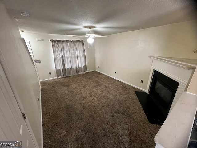 unfurnished living room featuring ceiling fan, dark colored carpet, and a textured ceiling