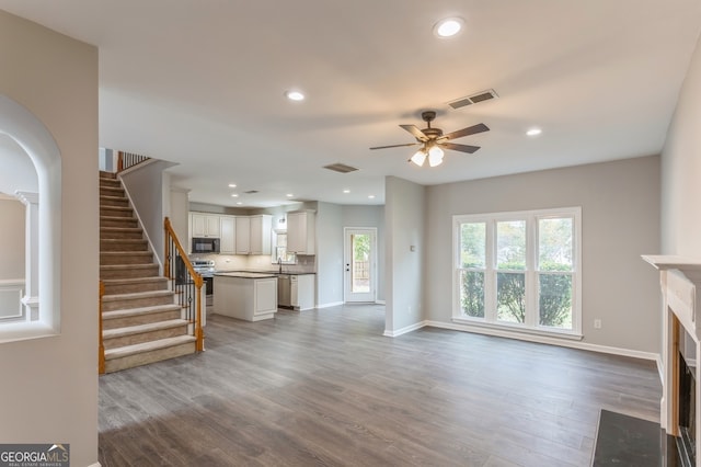 unfurnished living room featuring a healthy amount of sunlight, hardwood / wood-style flooring, sink, and ceiling fan