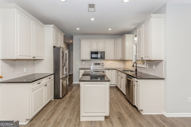 kitchen featuring a kitchen island, white cabinets, light hardwood / wood-style flooring, and stainless steel appliances