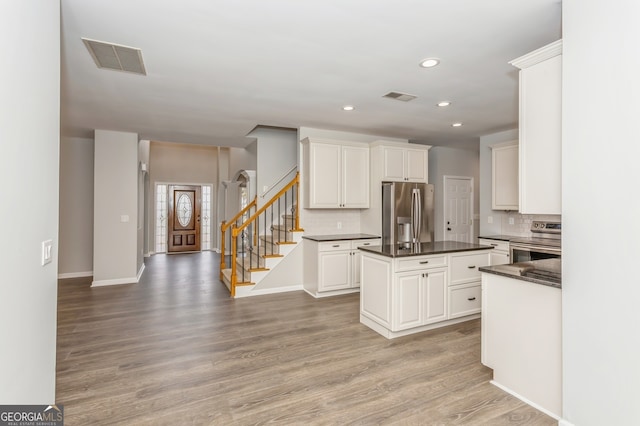 kitchen with wood-type flooring, appliances with stainless steel finishes, a center island, and white cabinetry