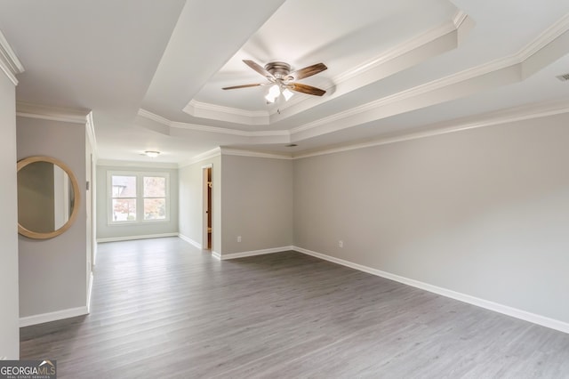 spare room with ornamental molding, hardwood / wood-style flooring, a tray ceiling, and ceiling fan