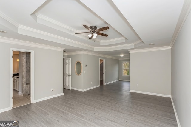 unfurnished room featuring ornamental molding, a tray ceiling, dark wood-type flooring, and ceiling fan