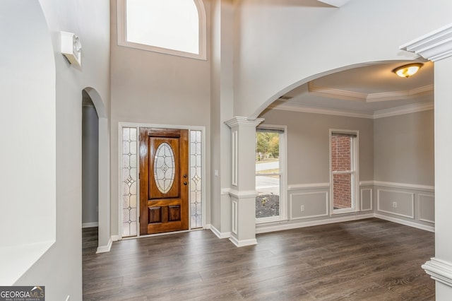 foyer entrance featuring ornamental molding, dark wood-type flooring, decorative columns, and a raised ceiling