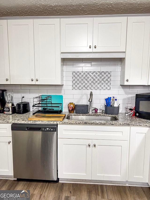 kitchen featuring white cabinetry, sink, light stone counters, stainless steel dishwasher, and hardwood / wood-style flooring