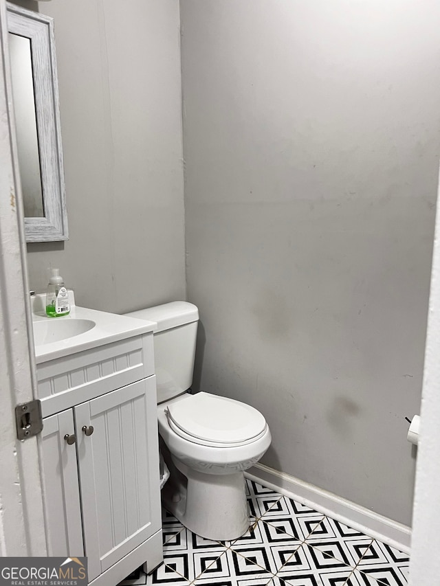 half bath featuring vanity, toilet, and baseboards