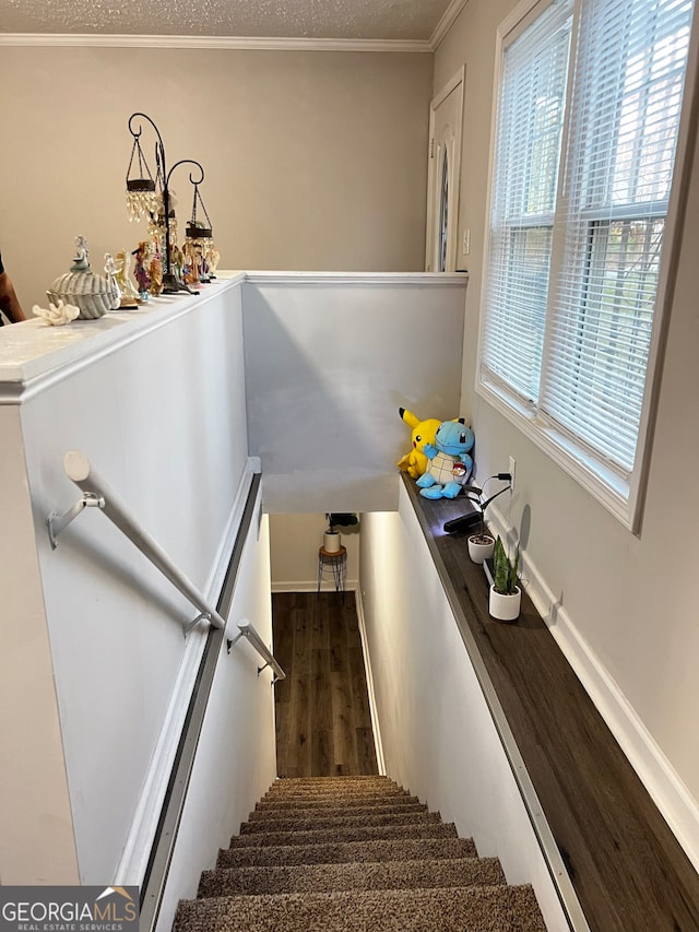 stairway with crown molding, a textured ceiling, baseboards, and wood finished floors