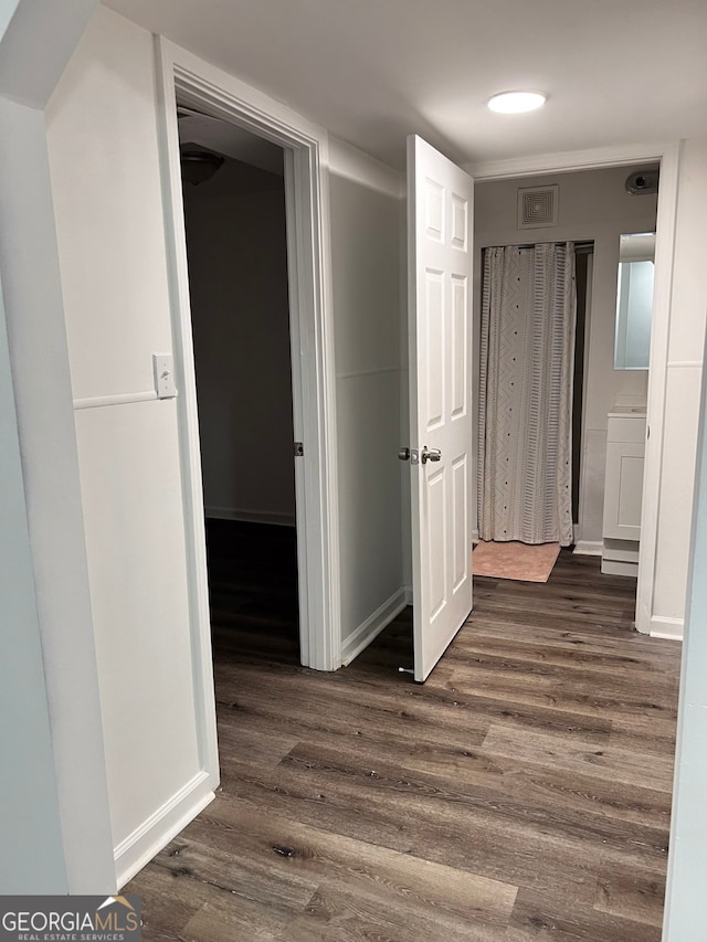 corridor featuring baseboards, visible vents, and dark wood finished floors