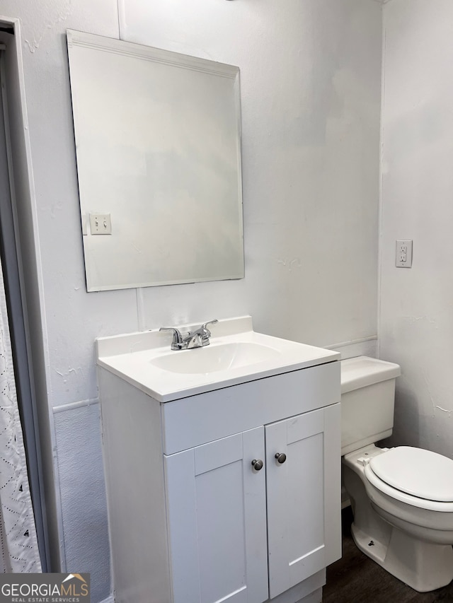 bathroom with toilet, wood finished floors, and vanity