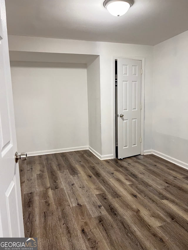 empty room featuring baseboards and dark wood finished floors