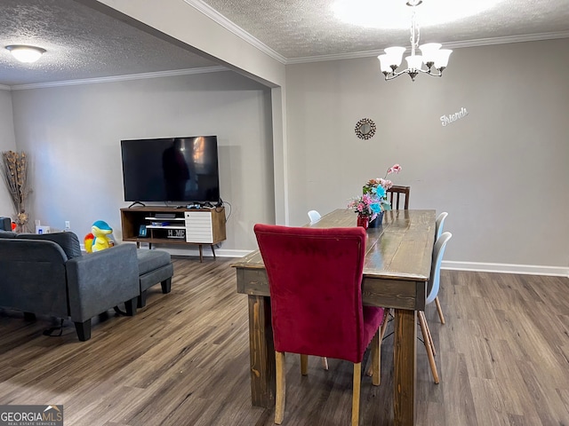 dining area featuring hardwood / wood-style flooring, a textured ceiling, crown molding, and an inviting chandelier