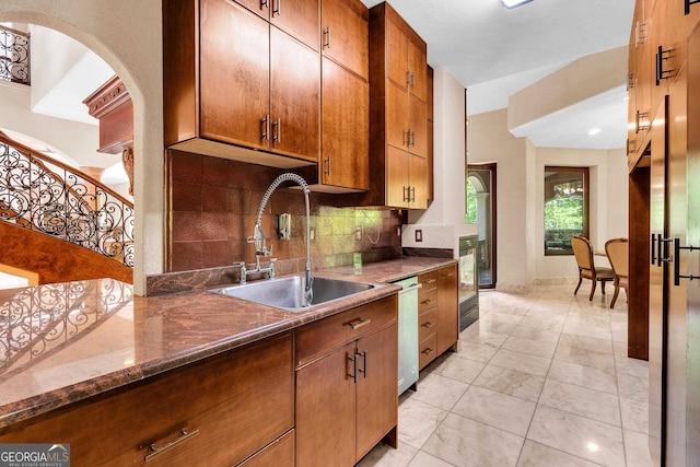 kitchen featuring dark stone counters, decorative backsplash, sink, and stainless steel dishwasher