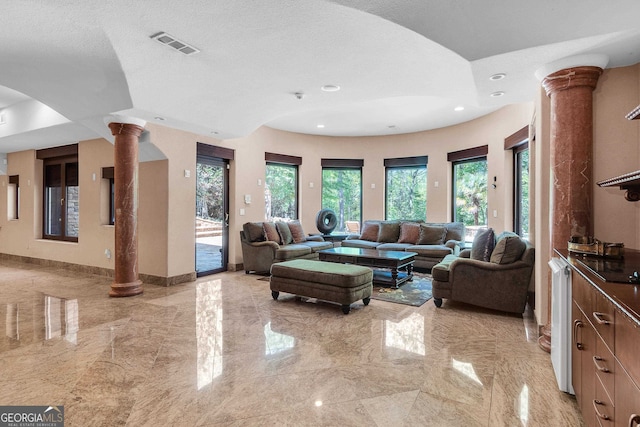 living room with decorative columns and a textured ceiling