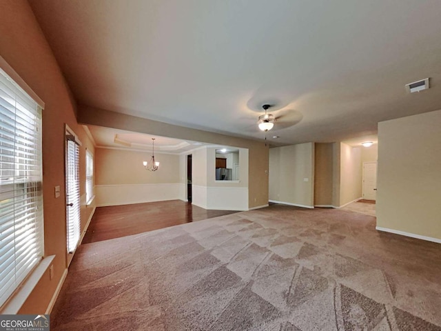 carpeted empty room featuring ornamental molding and ceiling fan with notable chandelier