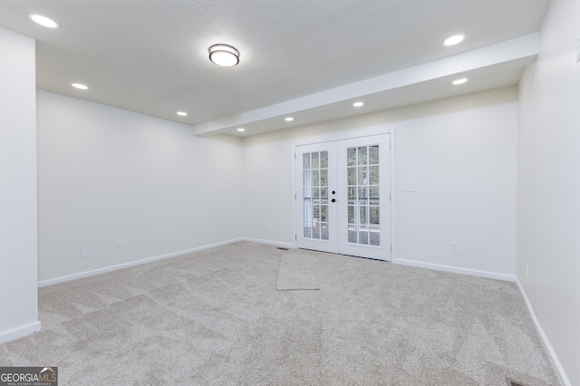 carpeted empty room featuring a textured ceiling and french doors