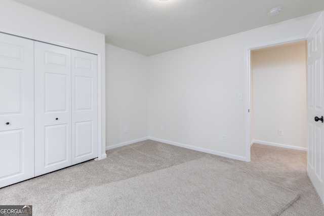 unfurnished bedroom with light colored carpet and a closet