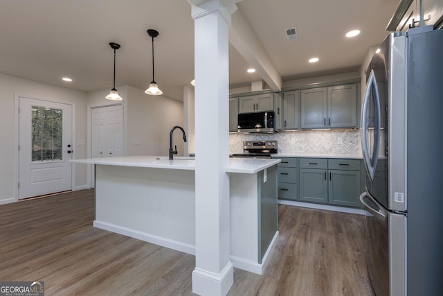 kitchen with stainless steel appliances, hardwood / wood-style flooring, pendant lighting, and ornate columns