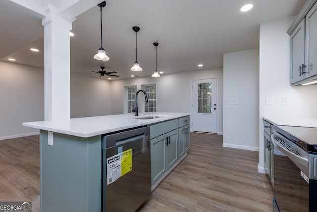 kitchen with stainless steel appliances, sink, an island with sink, and light hardwood / wood-style flooring