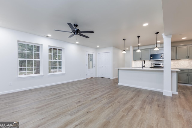 kitchen featuring light hardwood / wood-style flooring, gray cabinets, hanging light fixtures, and backsplash