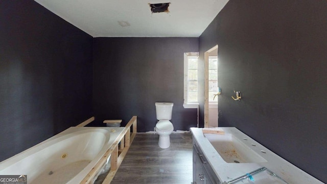 bathroom with toilet, hardwood / wood-style flooring, vanity, and a washtub