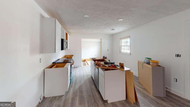 kitchen with light hardwood / wood-style floors, white cabinets, stainless steel appliances, and a textured ceiling