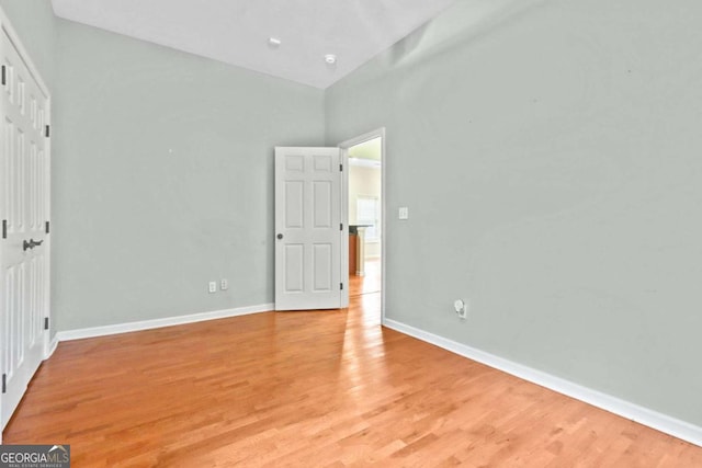 unfurnished bedroom with high vaulted ceiling and light hardwood / wood-style floors