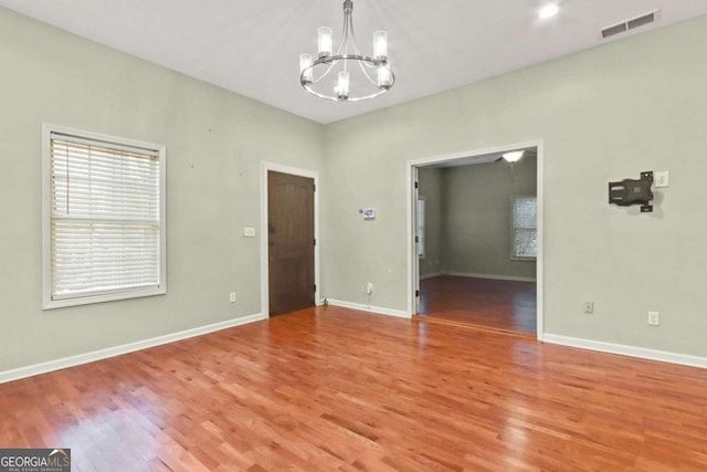 spare room featuring an inviting chandelier and hardwood / wood-style floors