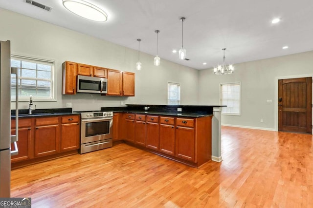 kitchen with pendant lighting, stainless steel appliances, a chandelier, and plenty of natural light