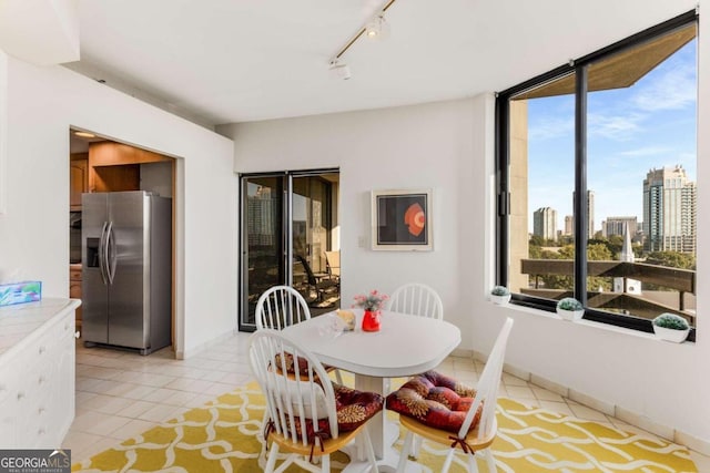 dining area with light tile patterned floors, a healthy amount of sunlight, and rail lighting