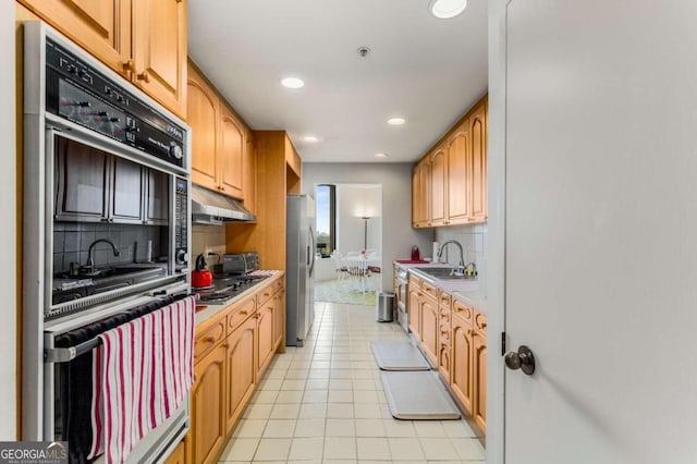 kitchen with tasteful backsplash, sink, light tile patterned floors, and stainless steel appliances