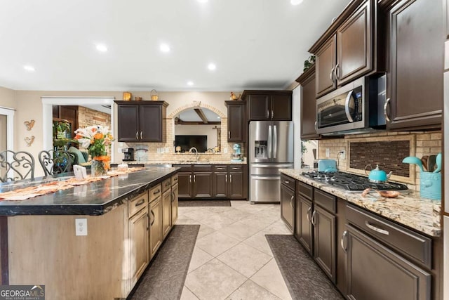 kitchen with backsplash, a kitchen island, stainless steel appliances, and dark brown cabinets