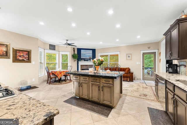 kitchen with recessed lighting, open floor plan, dark brown cabinets, stainless steel dishwasher, and dark stone countertops