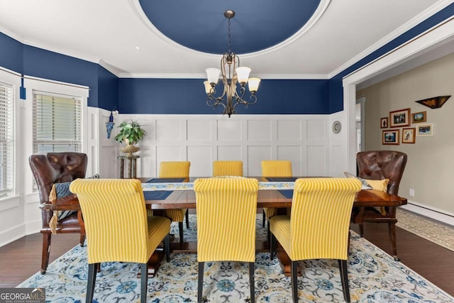 dining space with an inviting chandelier, crown molding, and wood finished floors