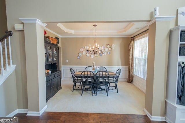 dining space featuring light hardwood / wood-style flooring, an inviting chandelier, a tray ceiling, and crown molding