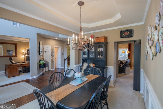 dining room featuring ornamental molding, dark wood-type flooring, a chandelier, and a raised ceiling