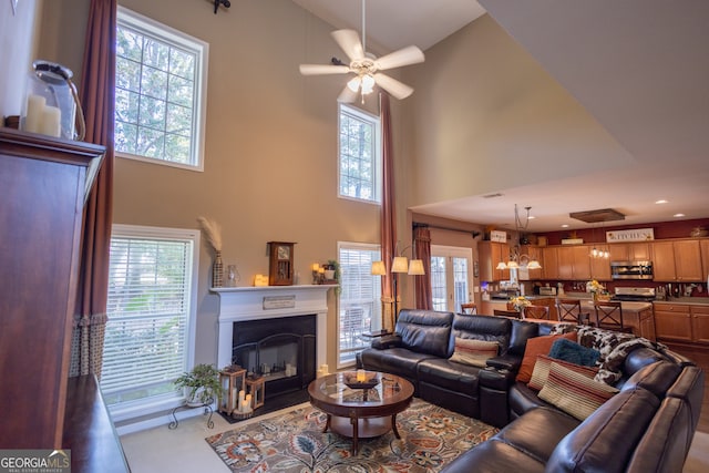 living room featuring ceiling fan, a towering ceiling, and plenty of natural light