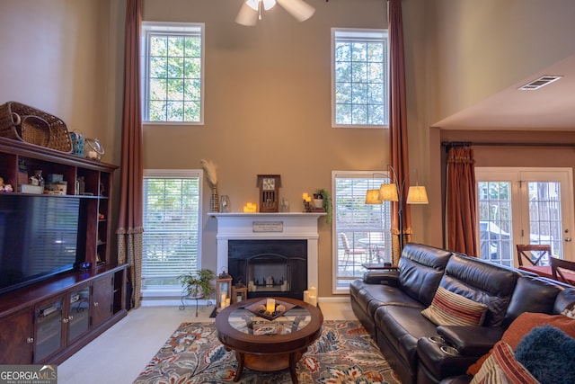 living room featuring ceiling fan, a towering ceiling, and a wealth of natural light