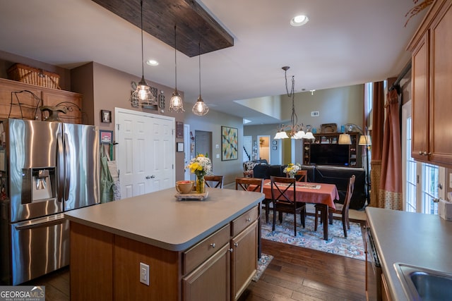 kitchen with appliances with stainless steel finishes, dark hardwood / wood-style floors, a center island, and decorative light fixtures