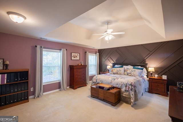 carpeted bedroom featuring ceiling fan and a tray ceiling