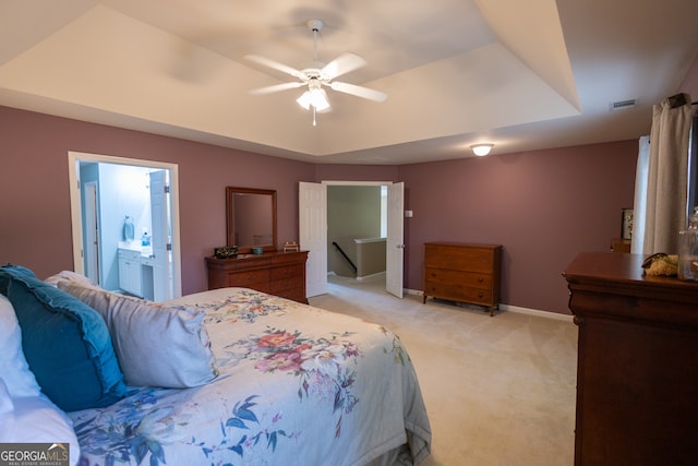 bedroom with connected bathroom, ceiling fan, light carpet, and a raised ceiling