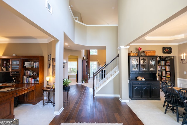 entrance foyer with crown molding, dark hardwood / wood-style floors, a high ceiling, and decorative columns