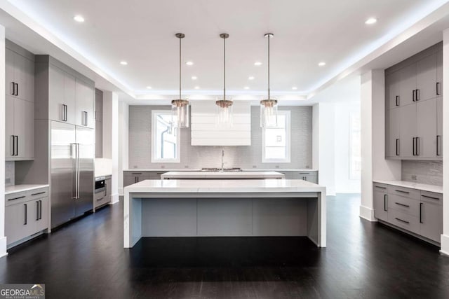 kitchen featuring gray cabinetry, a kitchen island, decorative light fixtures, stainless steel built in fridge, and dark hardwood / wood-style floors