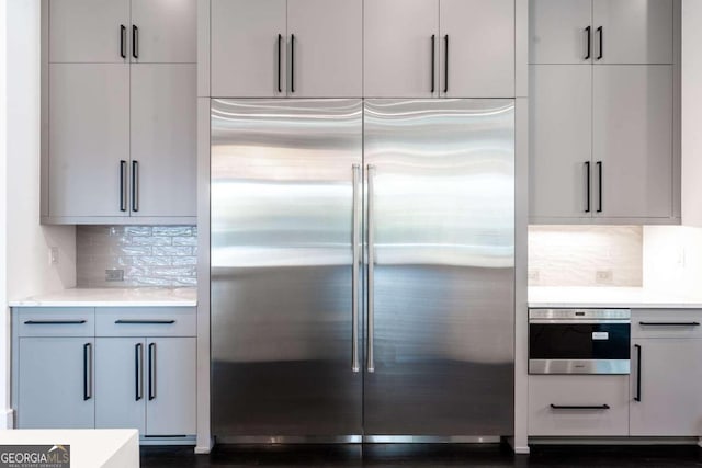 kitchen featuring decorative backsplash, appliances with stainless steel finishes, and dark hardwood / wood-style flooring