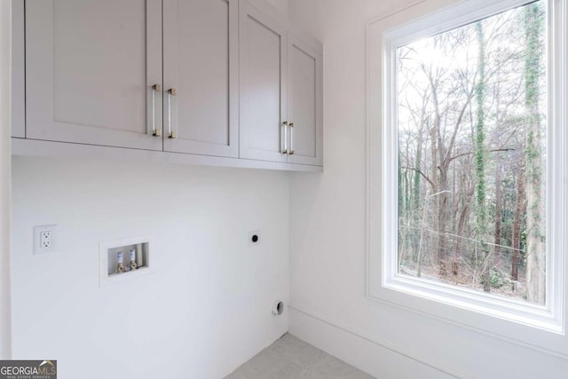 clothes washing area with hookup for an electric dryer, washer hookup, and cabinets