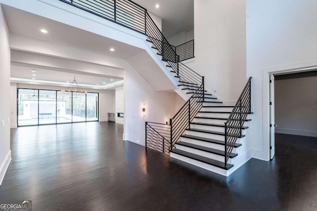 staircase featuring hardwood / wood-style floors, a chandelier, and a high ceiling