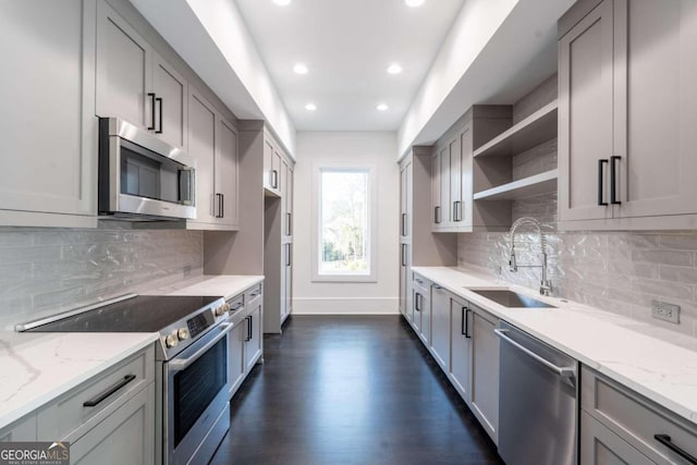 kitchen featuring dark hardwood / wood-style flooring, appliances with stainless steel finishes, light stone countertops, gray cabinetry, and sink