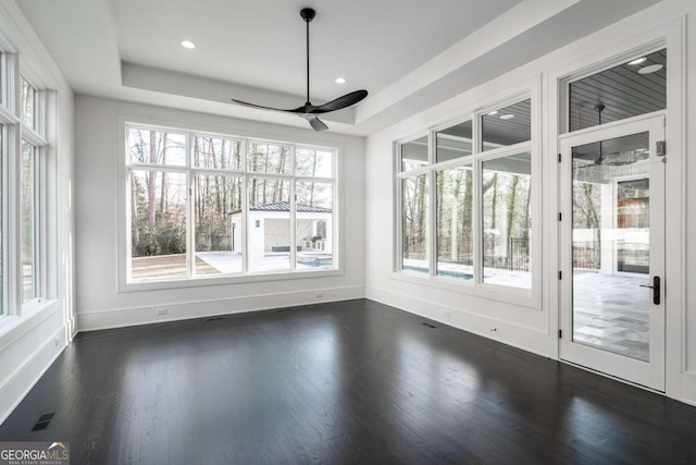 unfurnished sunroom with ceiling fan and a raised ceiling