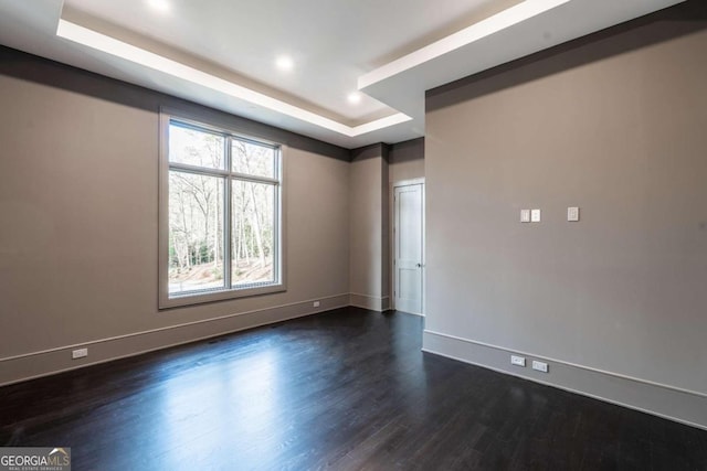 spare room featuring a tray ceiling and dark hardwood / wood-style flooring