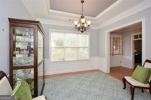 interior space with crown molding, a notable chandelier, wood-type flooring, and a raised ceiling